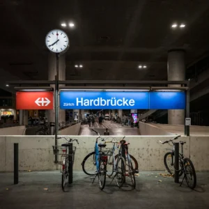 Bahnhof Zürich Hardbrücke bei Nacht mit Velos und beleuchtetem Bahnhofsschild
