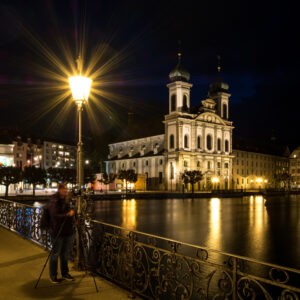 Ein Fotograf, der auf dem Rathaussteg in Luzern steht und im Hintergrund sieht man die Jesuitenkirche.