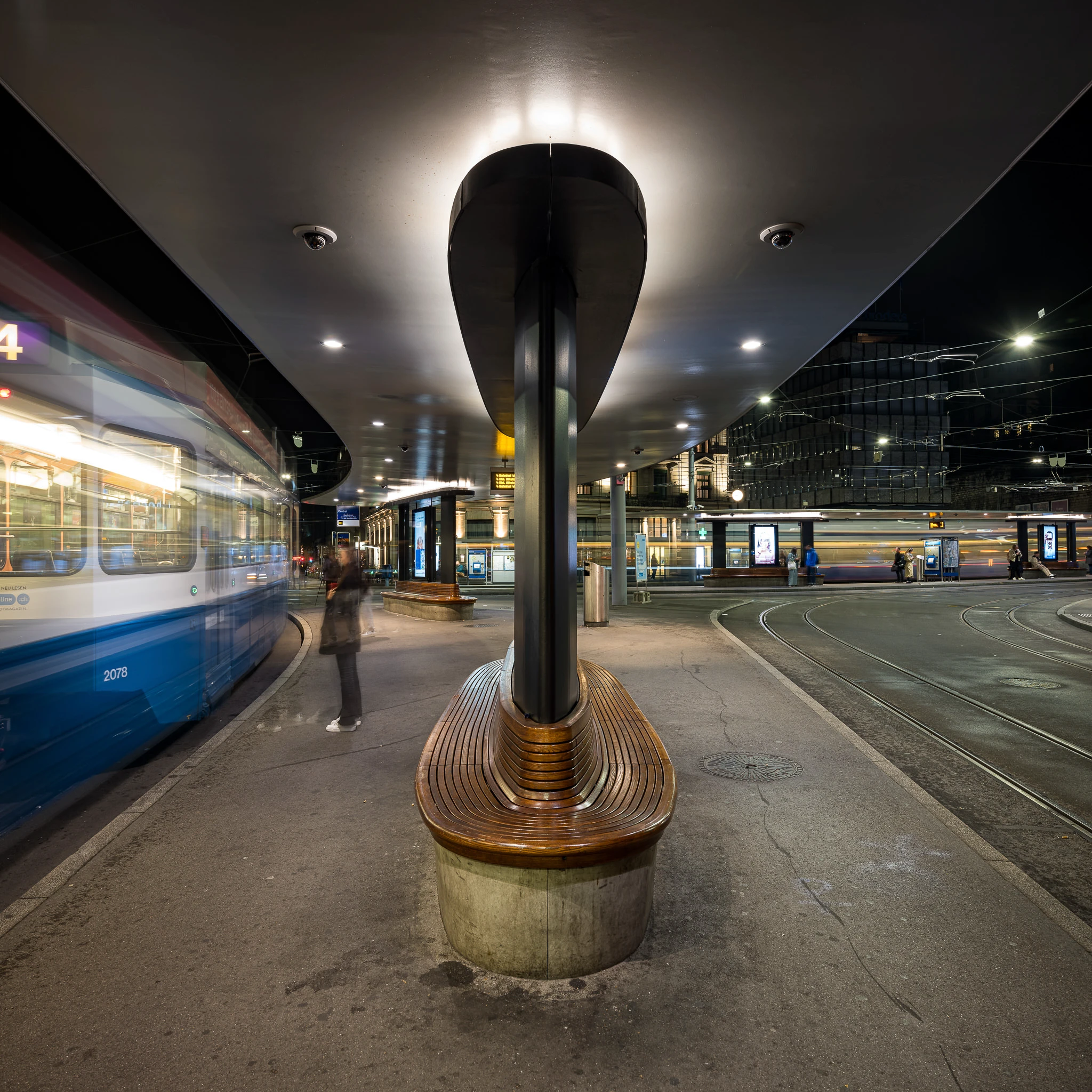 Tramhaltestelle am Zürich Central bei Nacht mit vorbeifahrendem Tram