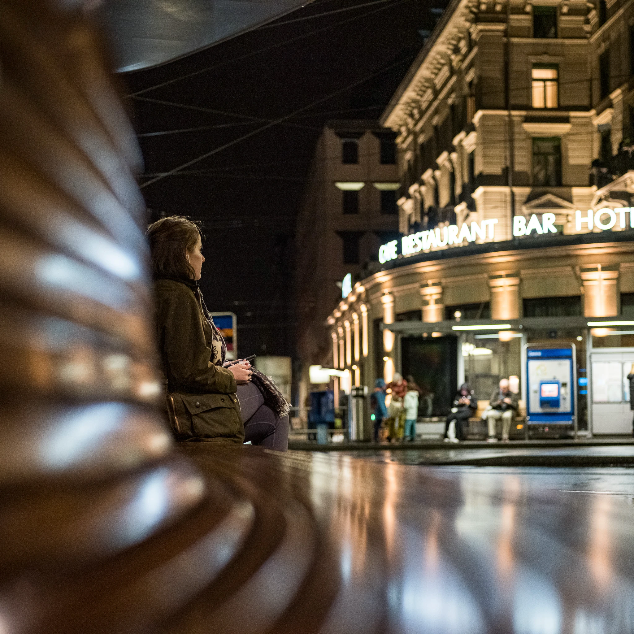 Person am Zürich Central mit beleuchteter Stadtlandschaft bei Nacht