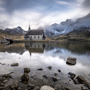 FotoKurs Melchsee-Frutt mit Kapelle vor verschneiten Bergen und ihrer Spiegelung im Melchsee.