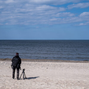 Eine Fotografin schaut an einem Starnd in Dänemark das Meer an.