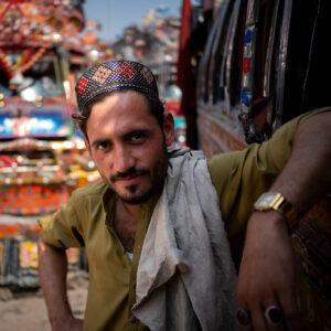 Porträt von einem Mann vor einem Bus in Pakistan.