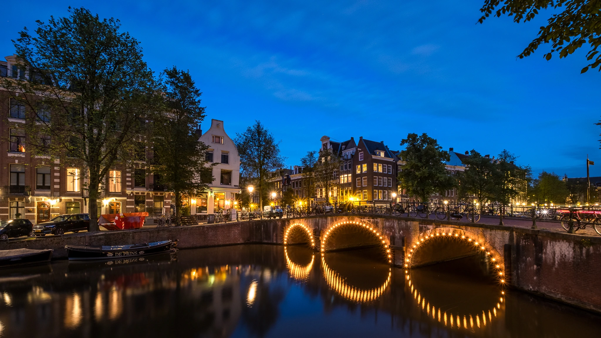 Blaue Stunde fotografieren – beleuchtete Brücke mit Lichtreflexen im Amsterdamer Kanal