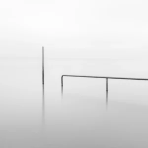 Minimalistisches Schwarzweissbild zweier metallener Elemente in einem stillen nebligen See, maximale Reduktion für ruhige Bilder in der Fotografie