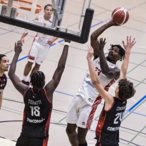 Basketballspieler beim Korbleger gegen zwei Verteidiger in der Sporthalle beim FotoKurs Sportfotografie.